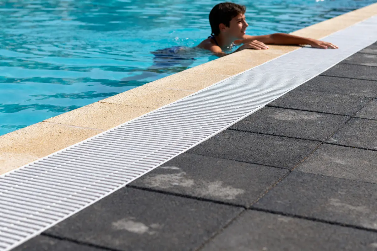Jeune homme nageant, carrelage noir et margelle beige pour aménager autour d'une piscine