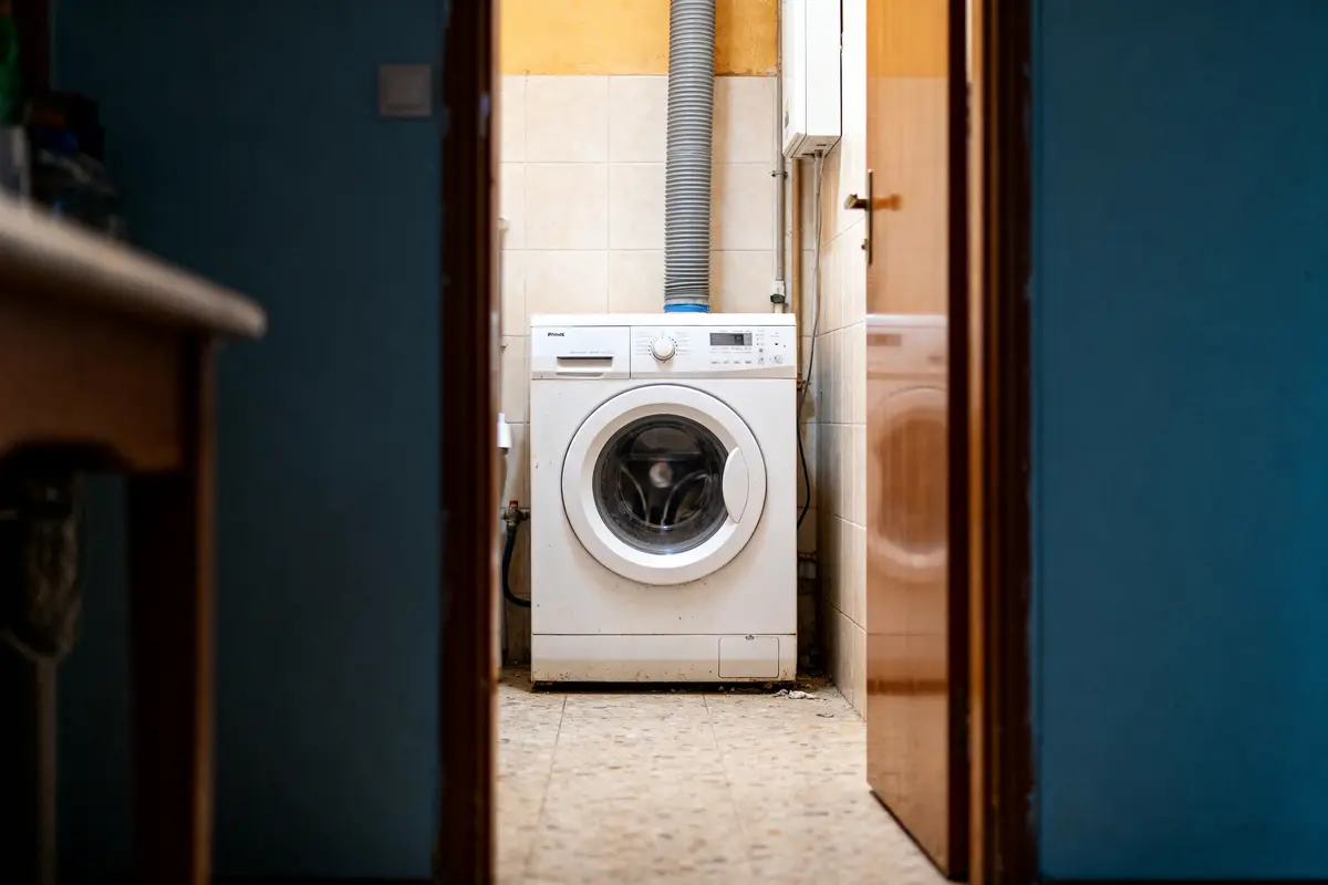 Lave-linge installé dans une buanderie avec tuyau, hauteur évacuation lave linge optimisée