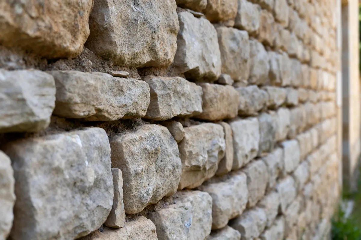 Mur pierre de taille composé de blocs gris beige alignés en perspective rapprochée