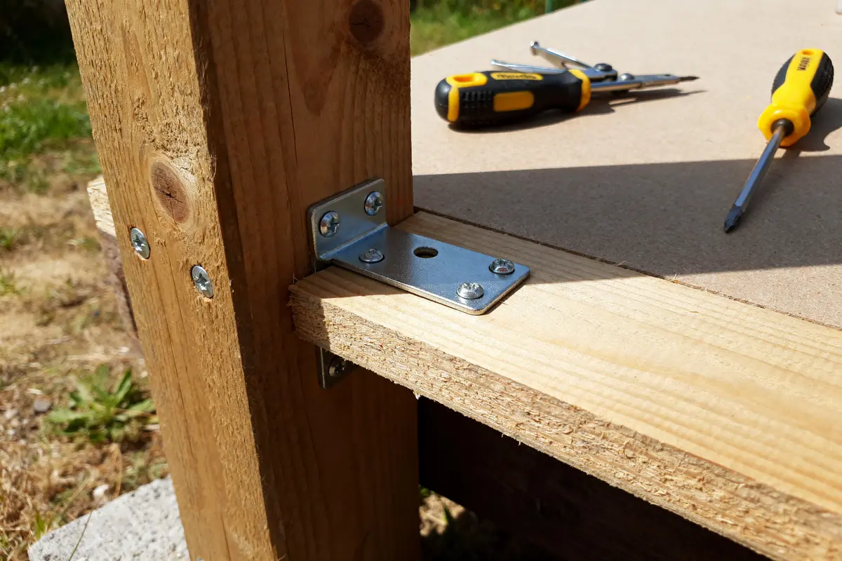Planche en bois avec outils démontre comment poser une charnière plate efficacement en extérieur