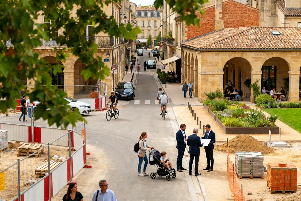 Rue animée du quartier de Bordeaux avec piétons, vélos et bâtiments historiques en journée